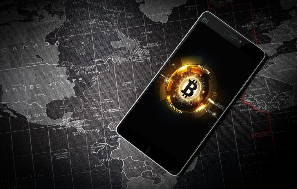 Bitcoin auf einem Smartphone vor Weltkarte